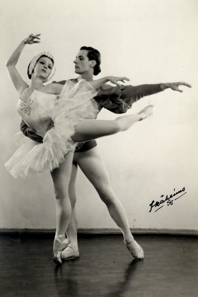 Kaksi balettiotanssijaa mustavalkoisessa kuvassa, jossa on vaalea tausta. Naistanssijalla on vaalea tutu ja päähine ja hän seisoo kärkitossulla yhden jalan varassa. Miestanssija seisoo hänen takanaan ja hänen toinen kätensä on naistanssijan vyötäisillä. 