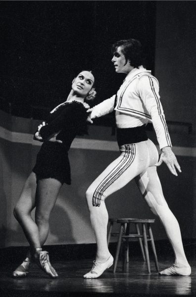 Mustavalkoinen kuva. Kaksi balettitanssijaa seisoo. Naistanssijalla on kädet puuskassa ja hän katsoo miestanssijaa olkansa yli. 